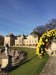 Picture of yellow flowers, a statue, and the Luxembourg Palace in the Luxembourg Gardens in Paris, France.