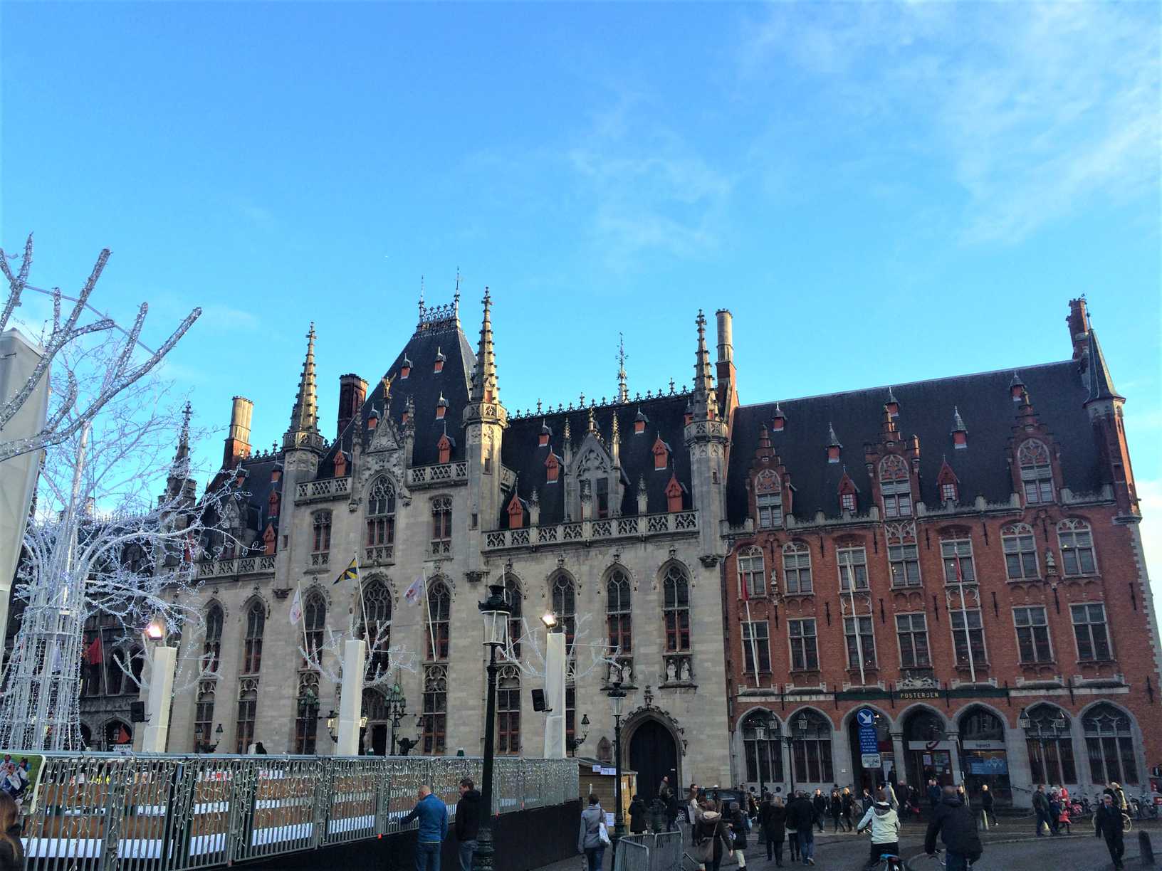 A picture of the Town Hall in Bruges, Belgium with an ice rink, Christmas decorations, and people in the forefront.