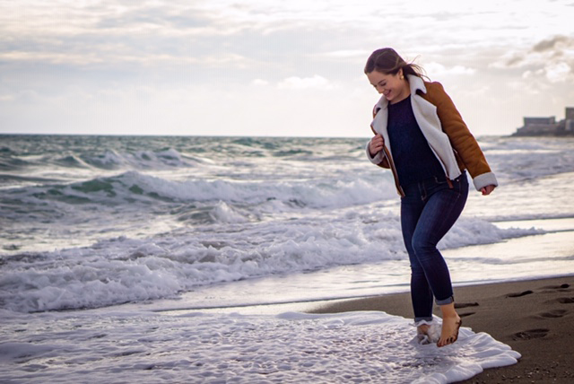 Carrie walking through the waves at the beach while smiling.