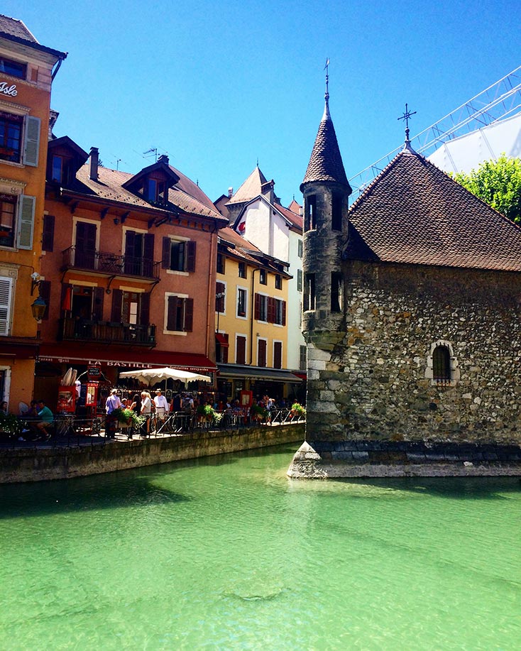 The canal in Annecy, France with the stone prison in the center. Colorful buildings are on the other side of the canal.