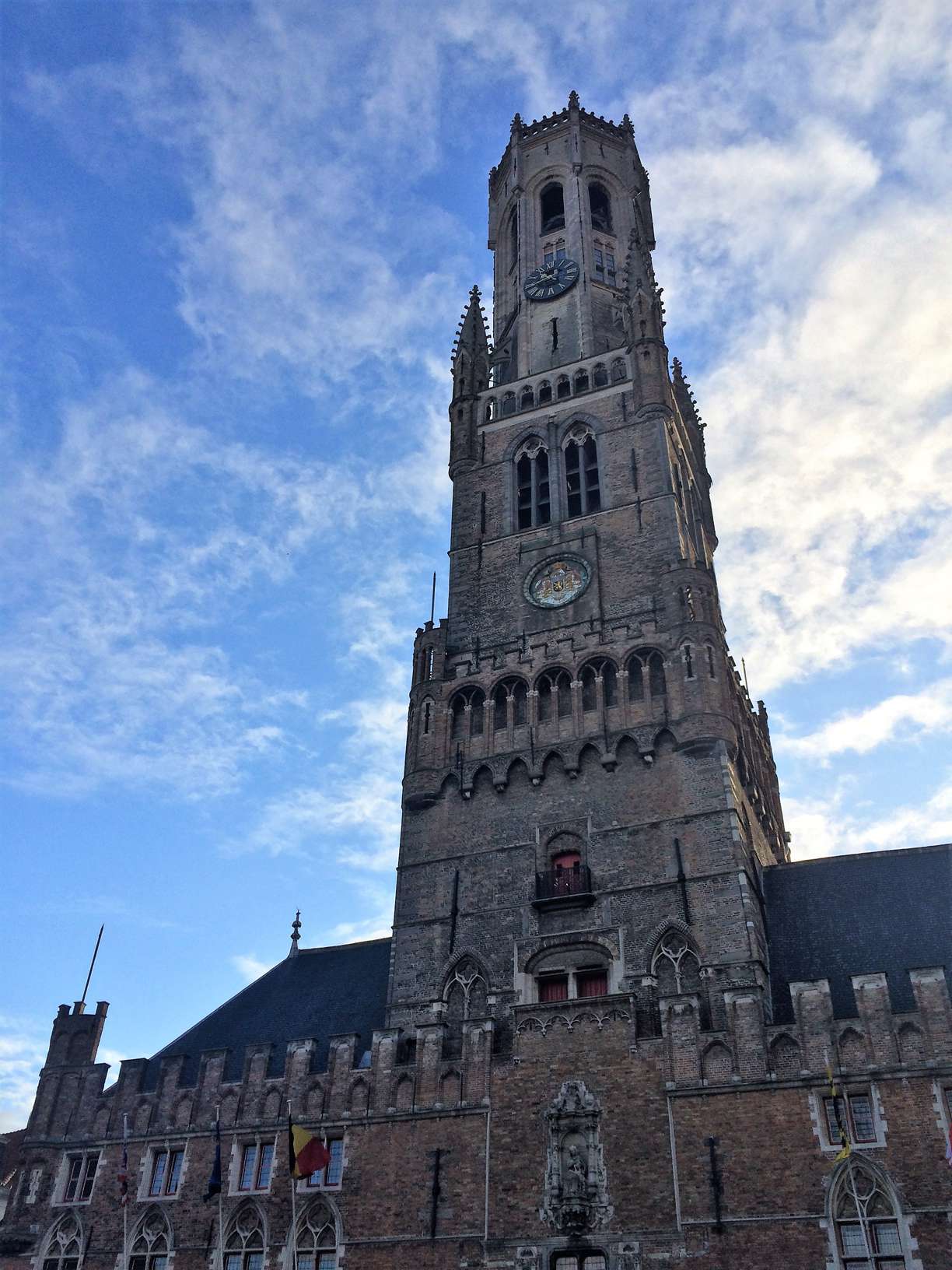 A picture of the belfry in Bruges, Belgium with a blue sky and some clouds in the background.