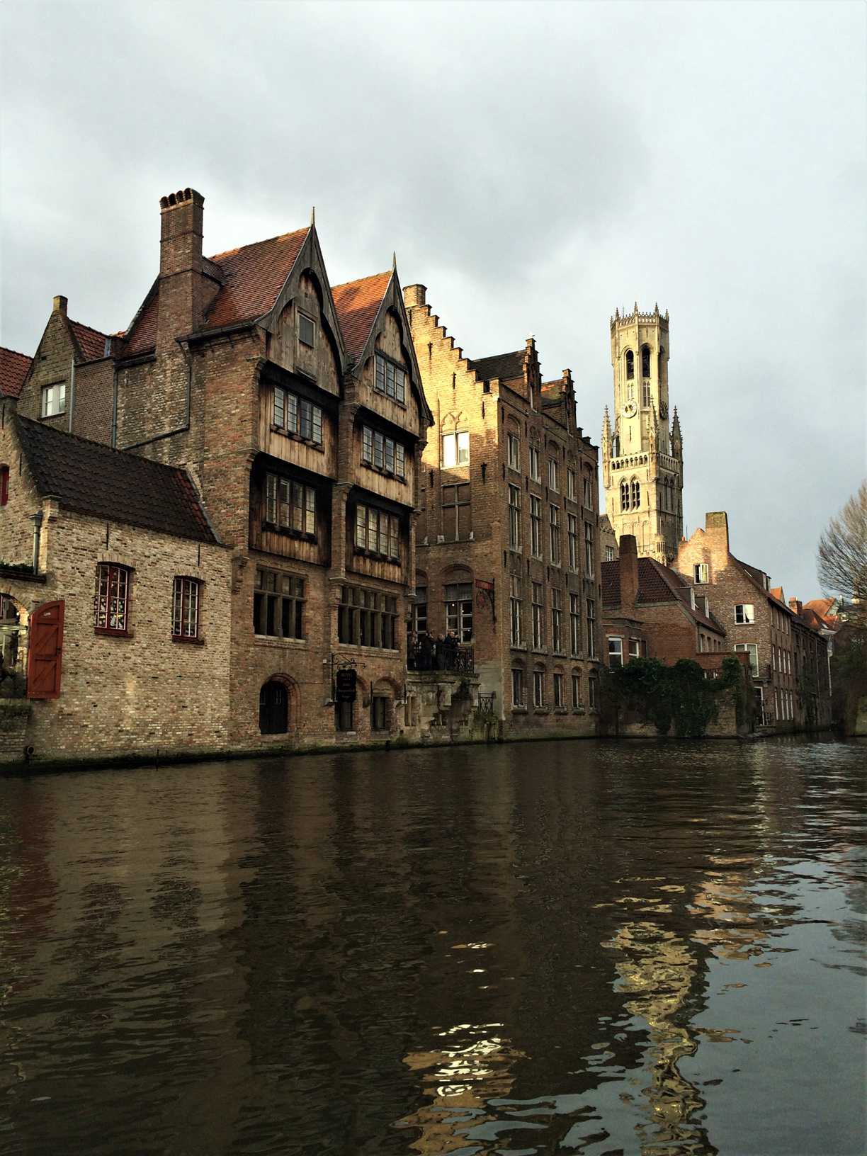 A picture of the oldest wooden buildings in Bruges, Belgium as seen from a boat on the canal.