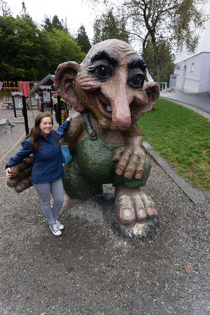A picture of a young woman standing next to a large wooden troll in Bergen, Norway.