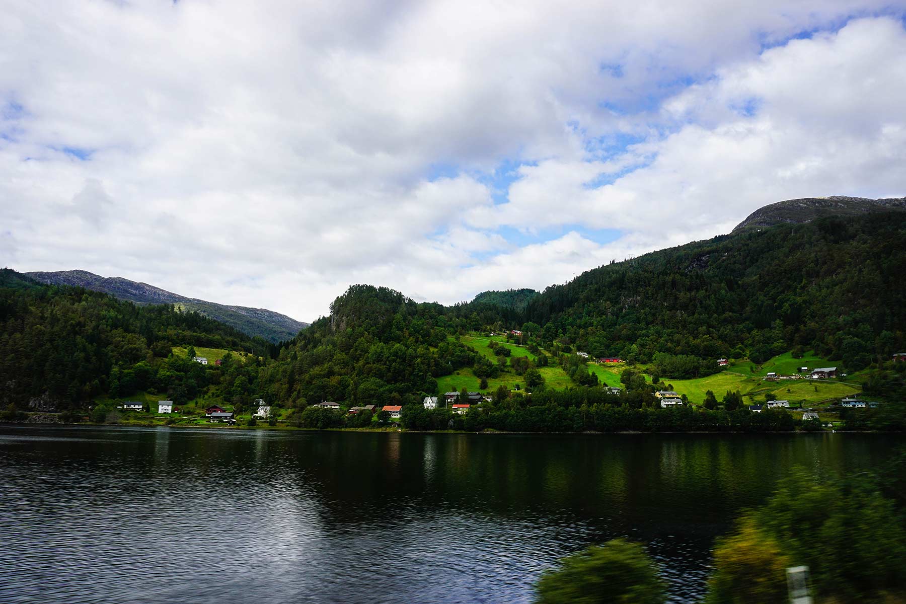 A picture of a lake with rolling green hills and trees in the background.