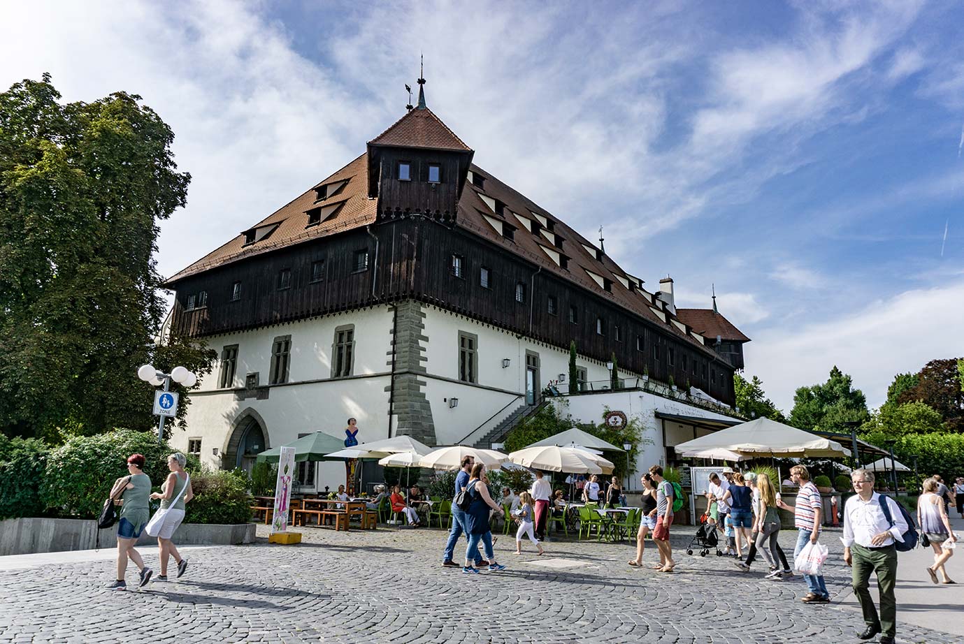 A medieval building in Konstanz, Germany that is half wood and half plaster. There are tables and umbrellas outside of the building.