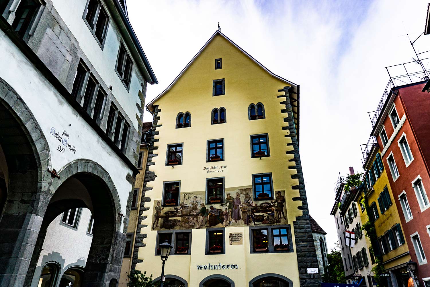 Traditional German buildings. One on the left says 1377 and one yellow building with a fresco on a street in Konstanz, Germany.