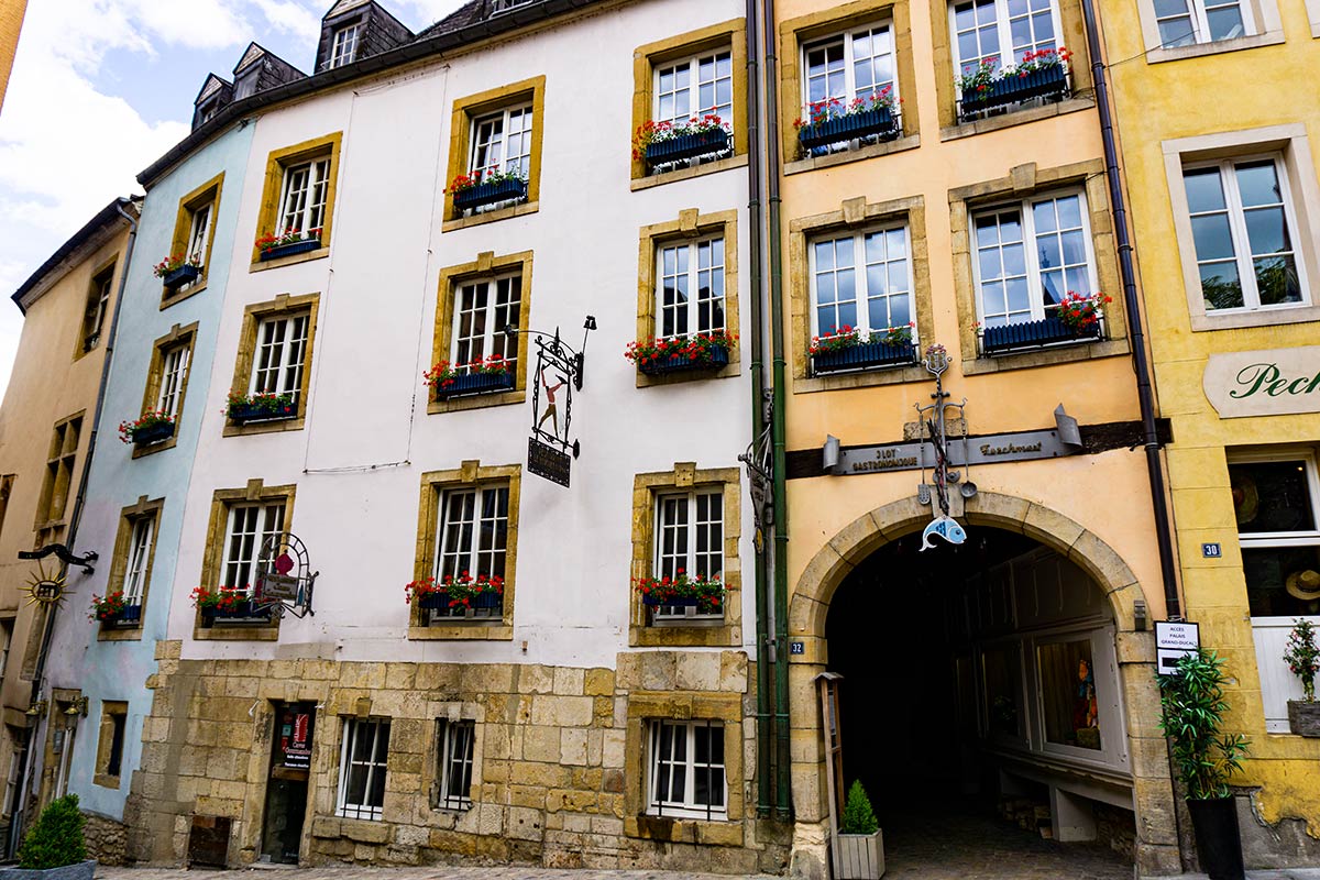 Old houses with flower boxes in the city center of Luxembourg City. Metal signs hang ourside of each building.