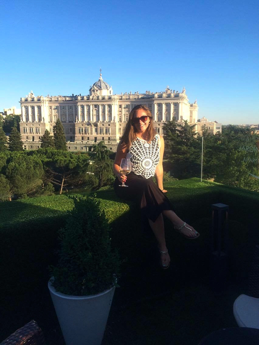 Picture of a girl at a rooftop bar in front of a palace in Madrid, Spain.