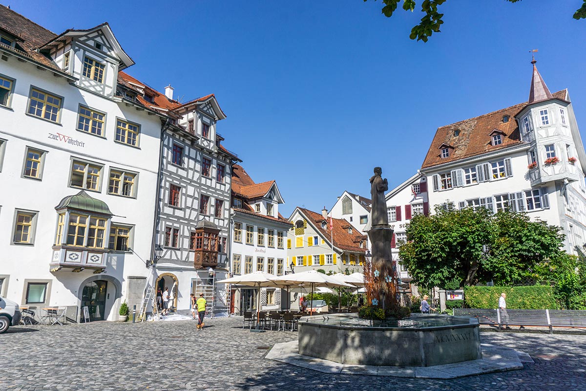 A charming plaza in Saint Gallen, Switzerland with colorful timbered buildings and a statue in the center.