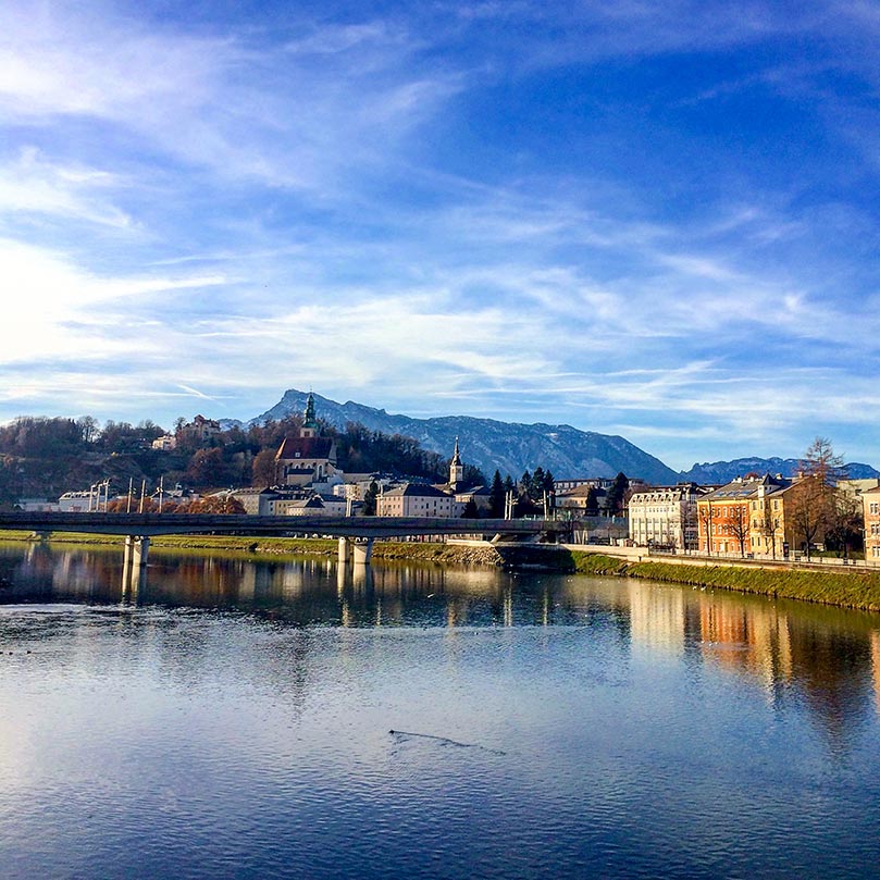 A lake with a the town of Salzburg, Austria behind it and mountains in the background.