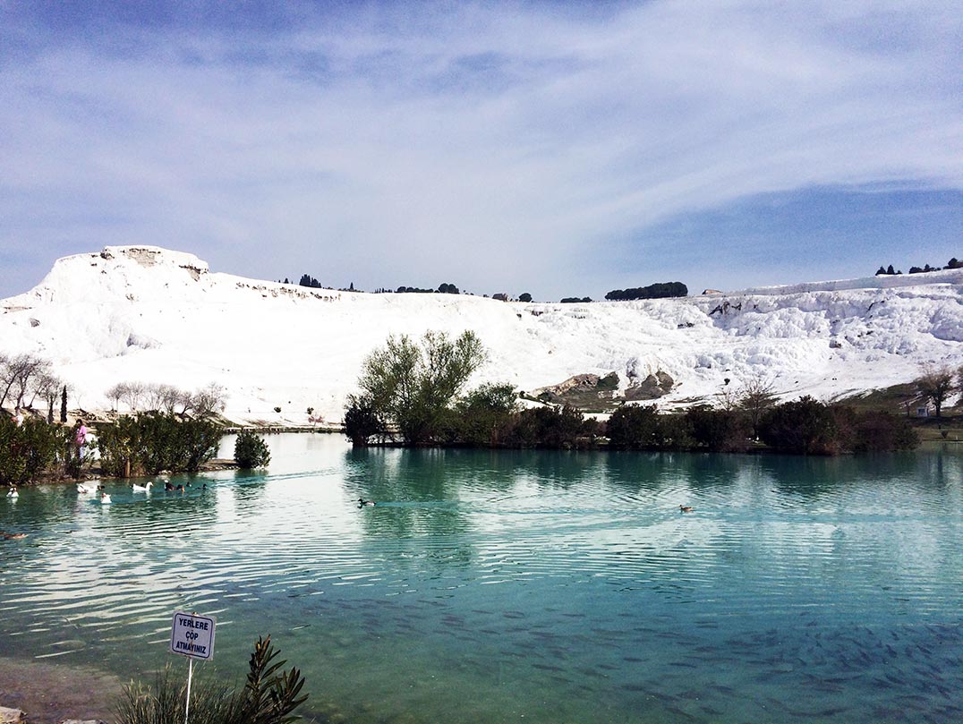 A turquoise lake and the white hills of Pamukkale in Turkey.